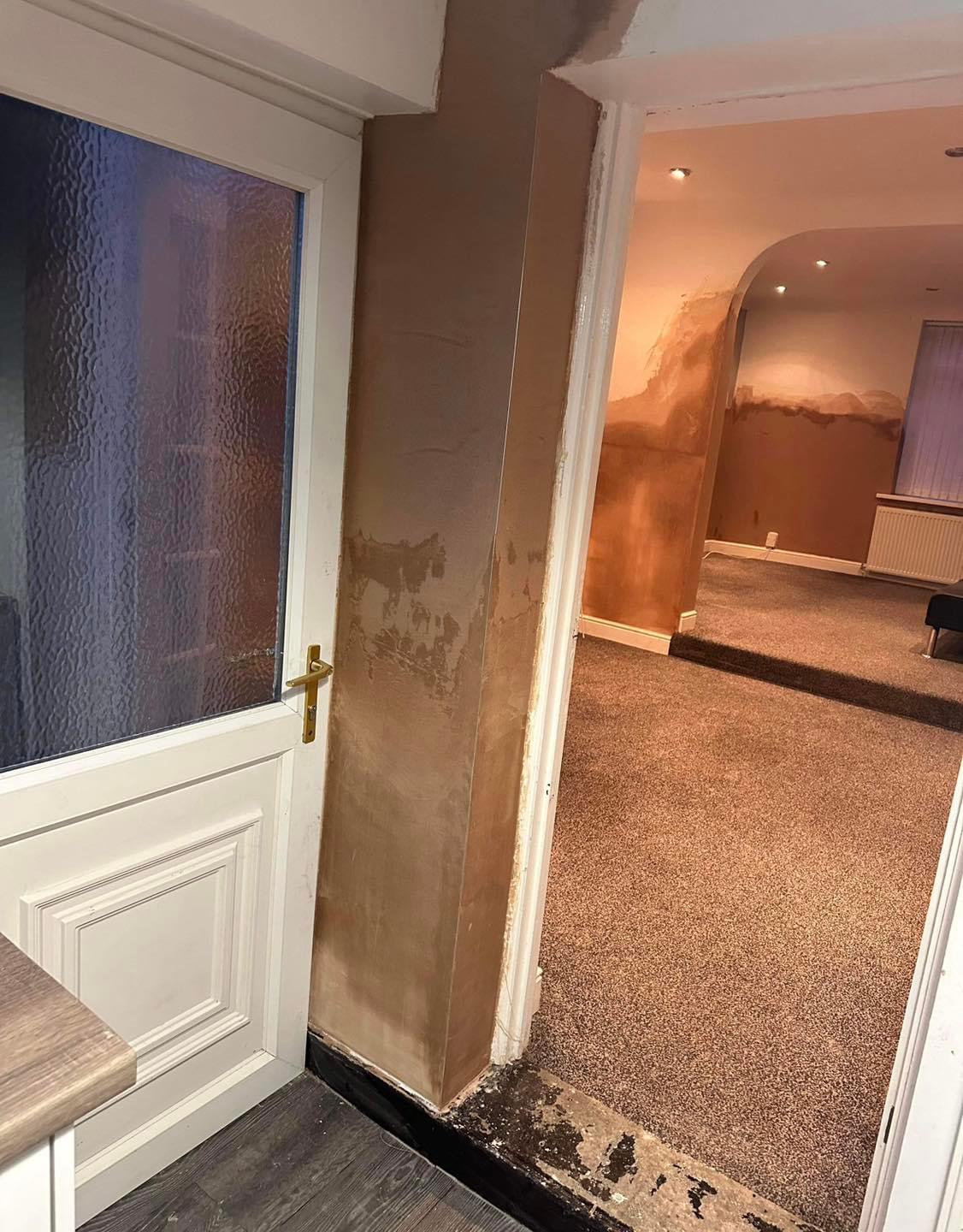 A hallway pillar and through-room with plaster patched up to a damp tide line