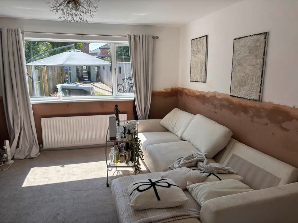 The same living room with the sofa and furniture back in place and the lower walls re-plastered